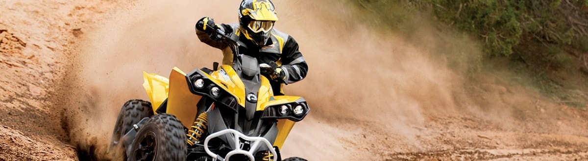 An individual in protective gear riding a Can-Am® ATV down a dirt hill.