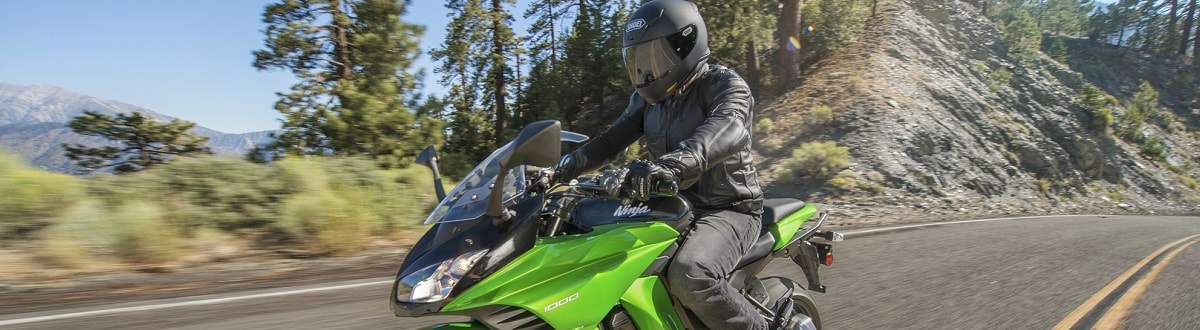 Individual in all black riding a black and green Kawasaki Ninja® on a high desert highway.